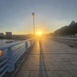 夏の夕暮れ、舞鶴橋から望む夕日と長い影が印象的な唐津の風景